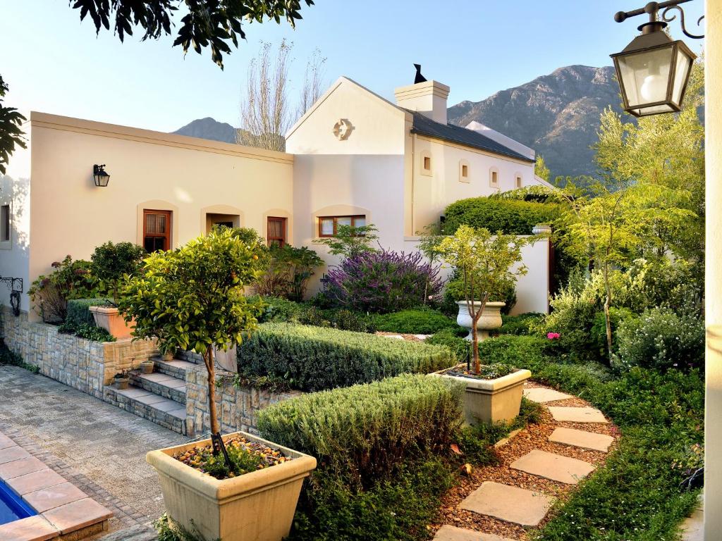 una casa con un jardín con árboles y arbustos en Petit & Grande Plaisir luxury self-catering, en Franschhoek