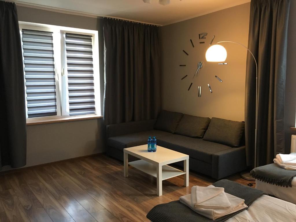 a living room with a couch and a clock on the wall at Apartament Elbląg Centrum in Elblag