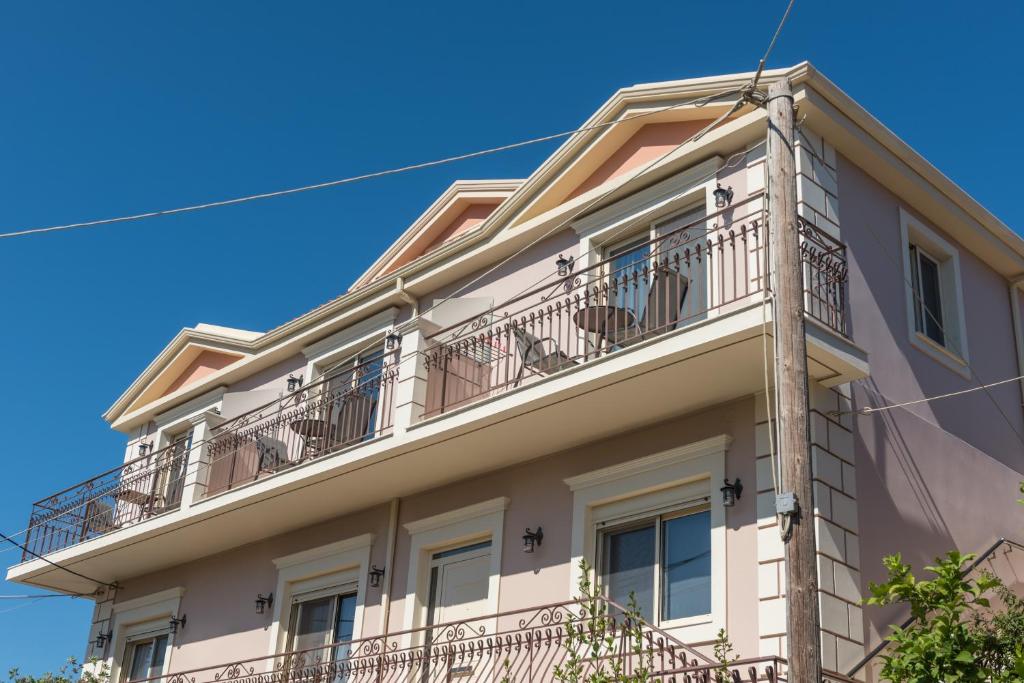an apartment building with balconies on a blue sky at Pansion Ermioni in Skala