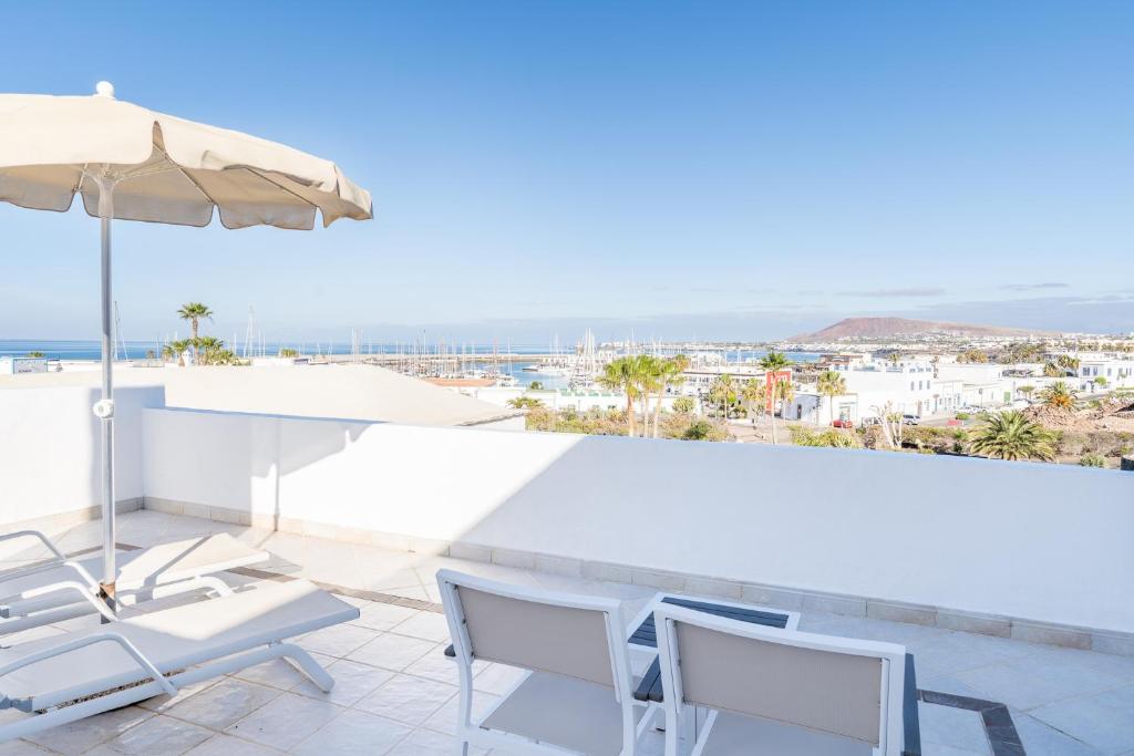 a patio with chairs and an umbrella and the ocean at Hotel LIVVO Volcán Lanzarote in Playa Blanca