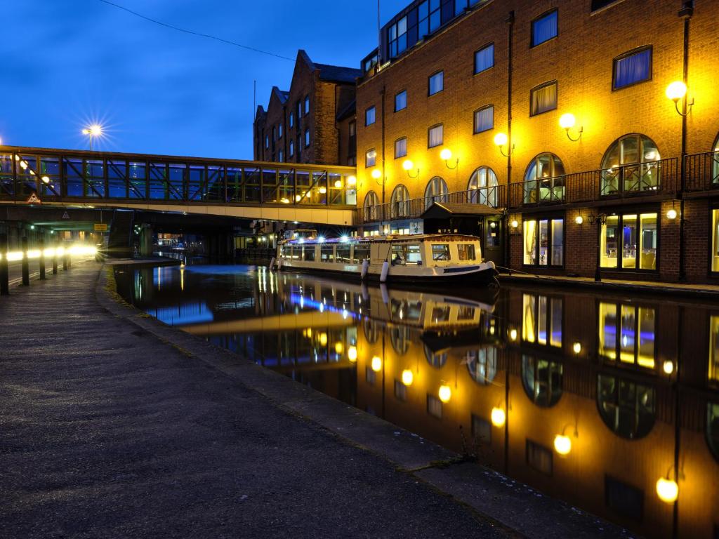 a canal with a bridge and buildings and a boat at MILL Hotel & Spa in Chester