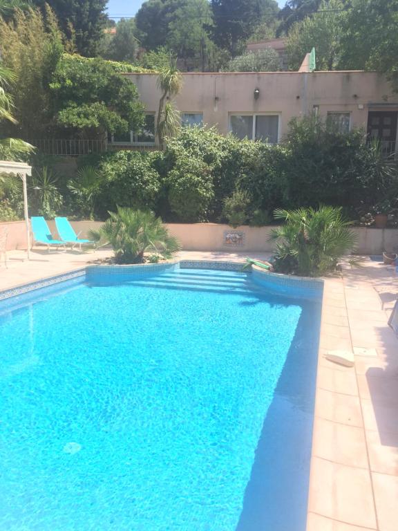 une piscine bleue avec deux chaises et un bâtiment dans l'établissement Magnifique Studio, à Sète