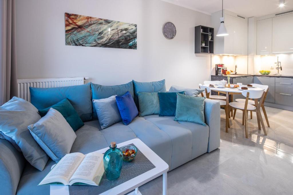 a living room with a blue couch and a table at Apartament BLUE Gardenia Dziwnów in Dziwnów