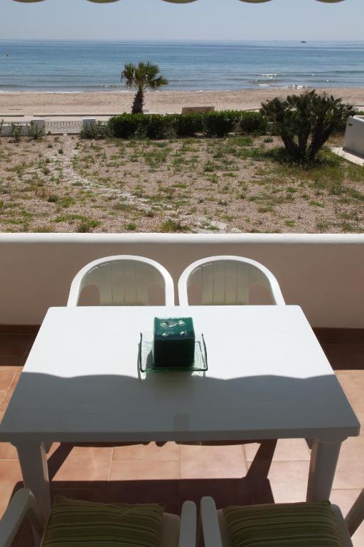 a table with a bag sitting on top of a balcony with the beach at Apartamentos LLorca in Platja de l’Almadrava