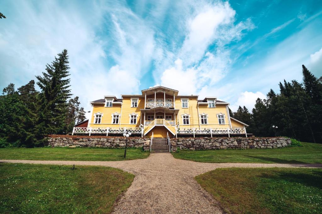 a large yellow house on top of a field at Karolineburg Manor House Hotel in Kajaani