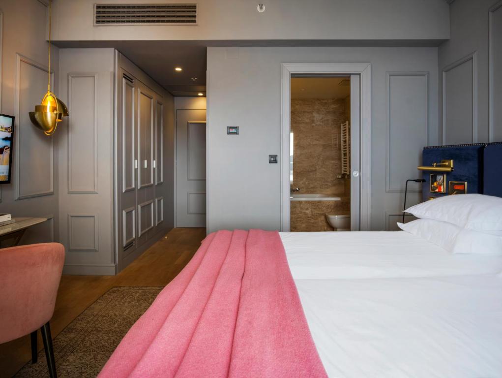 a bedroom with a large white bed and a pink rug at Hotel Excelsior in Dubrovnik