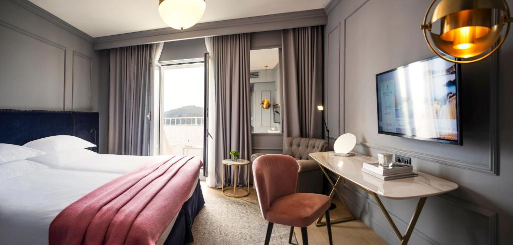 a hotel room with a bed and a desk and a television at Hotel Excelsior in Dubrovnik