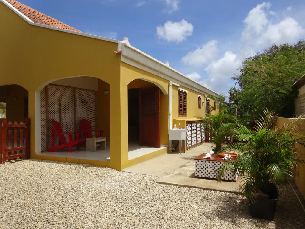 a yellow house with a porch and a patio at Yellow Palms in Kralendijk