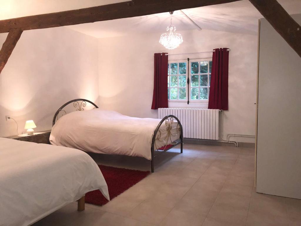 a bedroom with two beds and a window with red curtains at Maison en bord de seine in Boissise-le-Roi