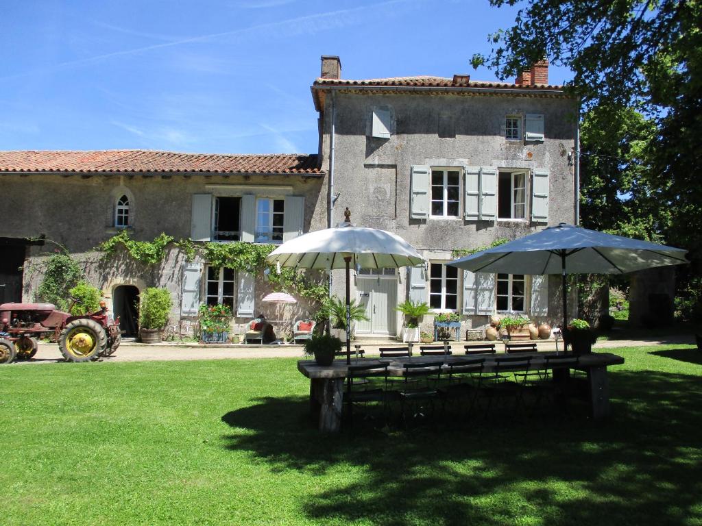 dos mesas de picnic con sombrillas frente a una casa en Domaine de Lalat - B&B with en-suite bathrooms all rooms with garden views, en Montembœuf