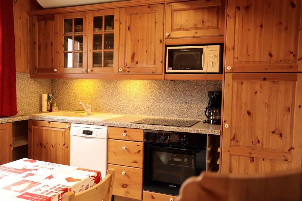 a kitchen with wooden cabinets and a stove top oven at Le Duplex d&#39;Aussois in Aussois