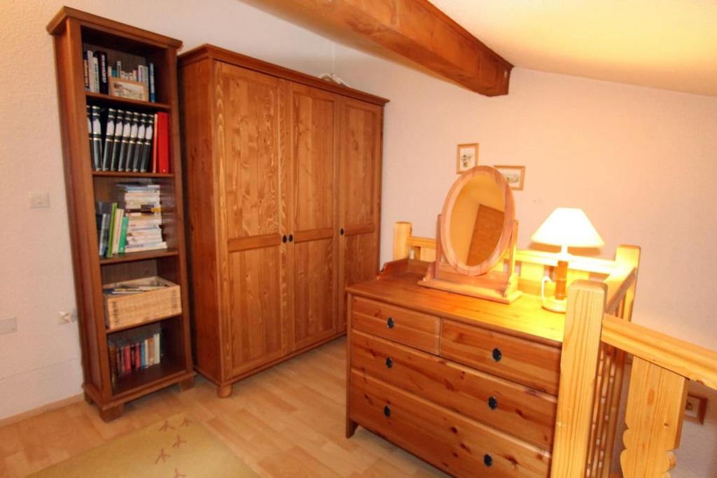 a bedroom with a wooden dresser with a mirror on it at Le Duplex d&#39;Aussois in Aussois