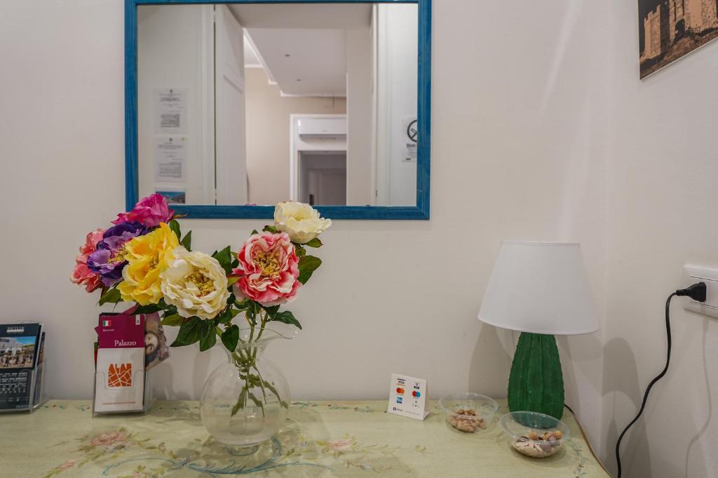 un vaso di fiori su un tavolo con uno specchio di Il Tarì Apartment a Palermo