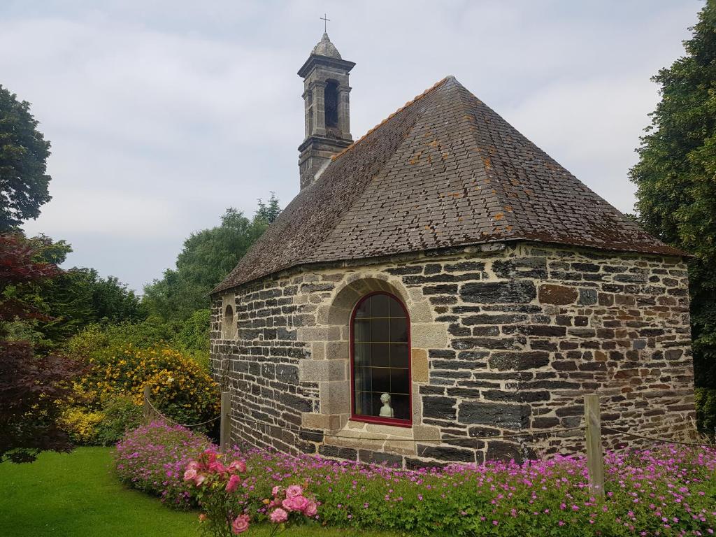 eine alte Steinkirche mit einem Fenster und Blumen in der Unterkunft Gîte Atypique Dans Une Chapelle in Briec