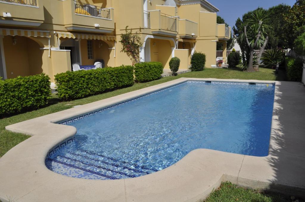 a swimming pool in front of a house at Acogedor adosado duplex in Els Poblets