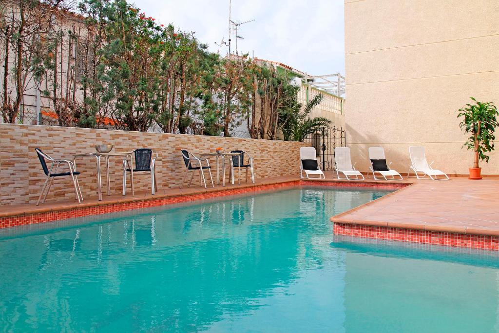 una piscina con sillas y una mesa en un edificio en Apartamentos Doña Carmen 3000, en Oropesa del Mar