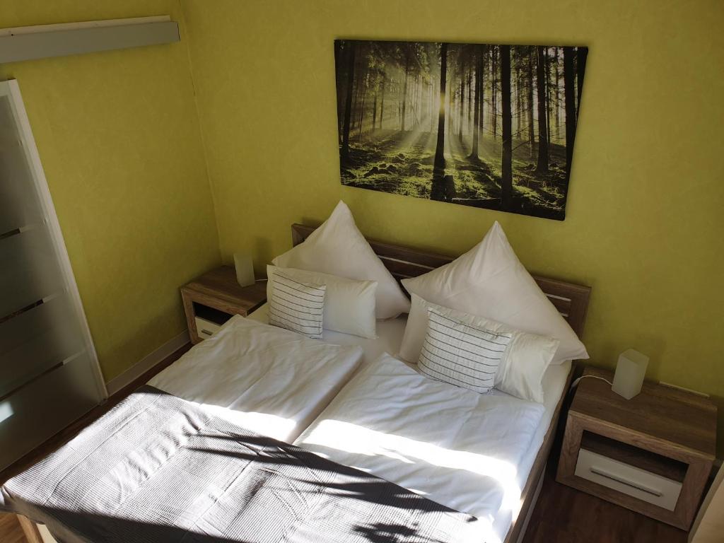 een bed met witte lakens en kussens in een slaapkamer bij Ferienwohnung Steiner in Homburg