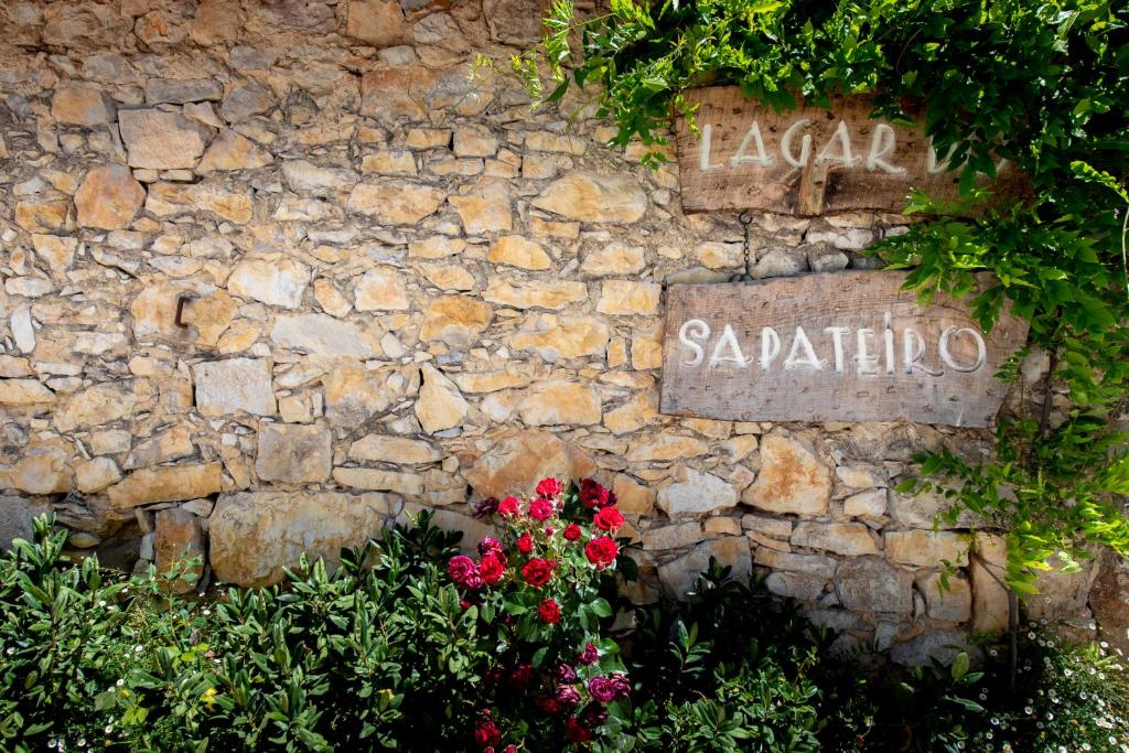 eine Steinmauer mit Blumen und einem Schild darauf in der Unterkunft Lagar do Sapateiro in Fontes
