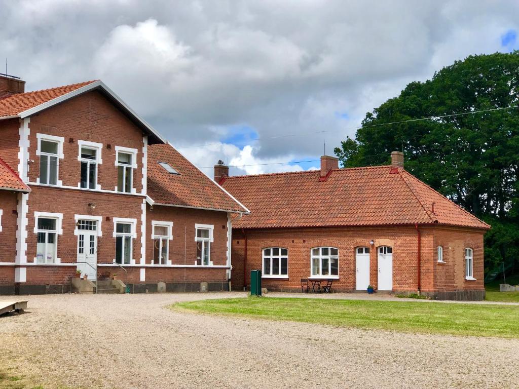 a red brick building with white windows and a dirt road at Pensionat Söderåsen in Ljungbyhed