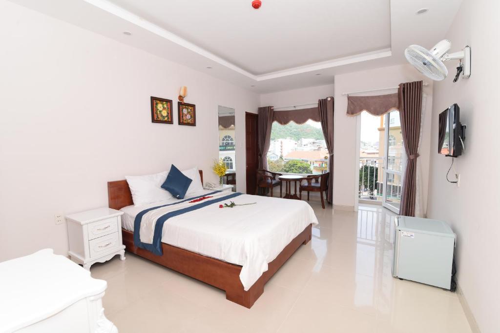 a white bedroom with a bed and a table at Kyo Hotel in Vung Tau