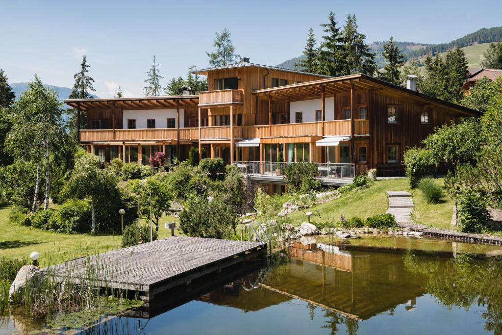 a house on a hill next to a lake at CHALET MARLENE - Ferienhaus in San Vigilio Di Marebbe