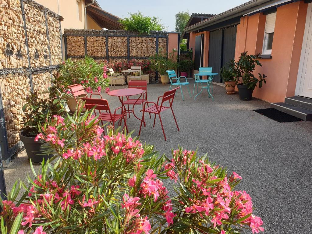 une terrasse avec des chaises, des tables et des fleurs roses dans l'établissement Chambre D´hôtes Léonie & Restaurant, à Druillat