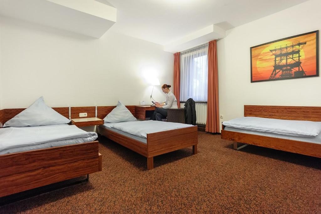 エッセンにあるHotel Böll Essenの三ベッドの部屋の机に座る男