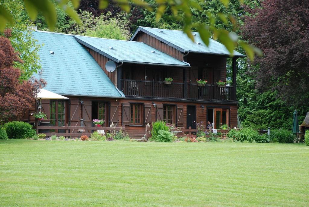uma grande casa de madeira com uma varanda e um quintal em Spruce Lake em Sauviat-sur-Vige