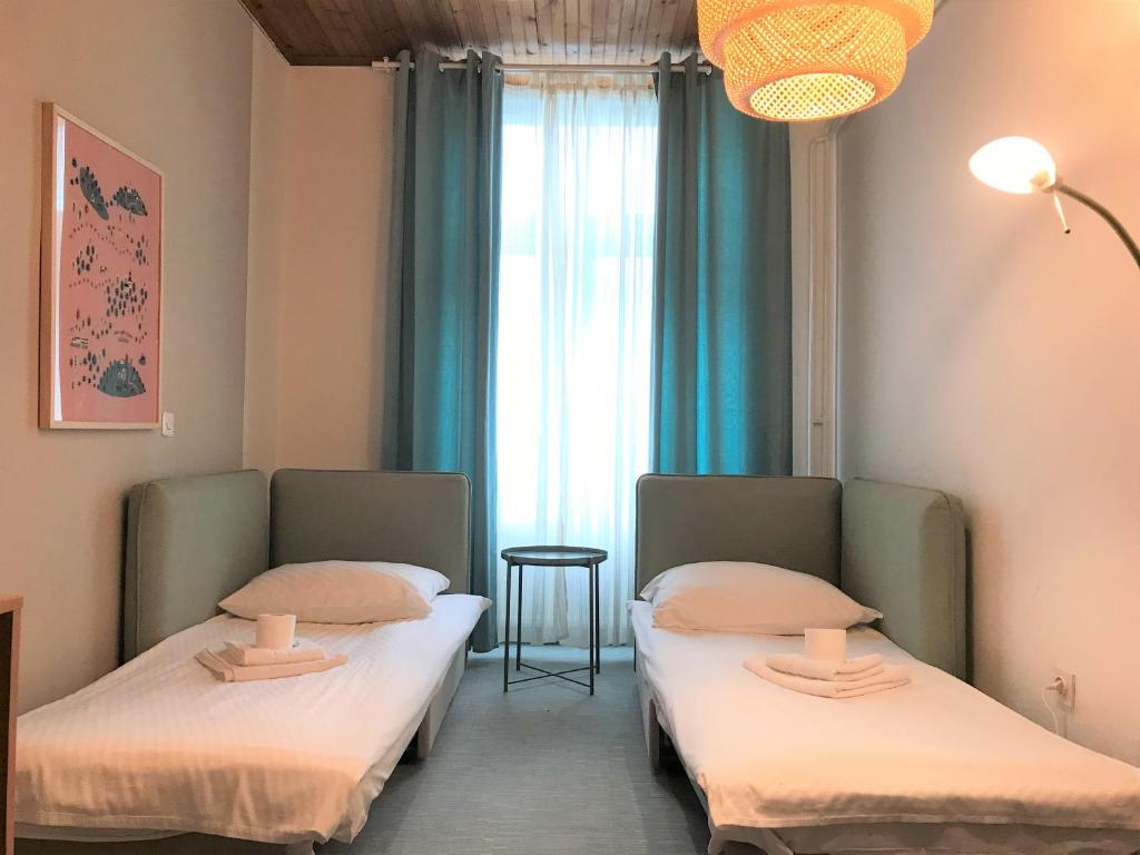 dwa łóżka w pokoju z oknem w obiekcie RTV Central S-Room w Lublanie