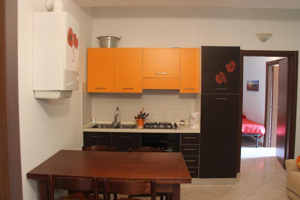 cocina con armarios naranjas y mesa de madera en Sul sentiero di Francesco, en Nocera Umbra
