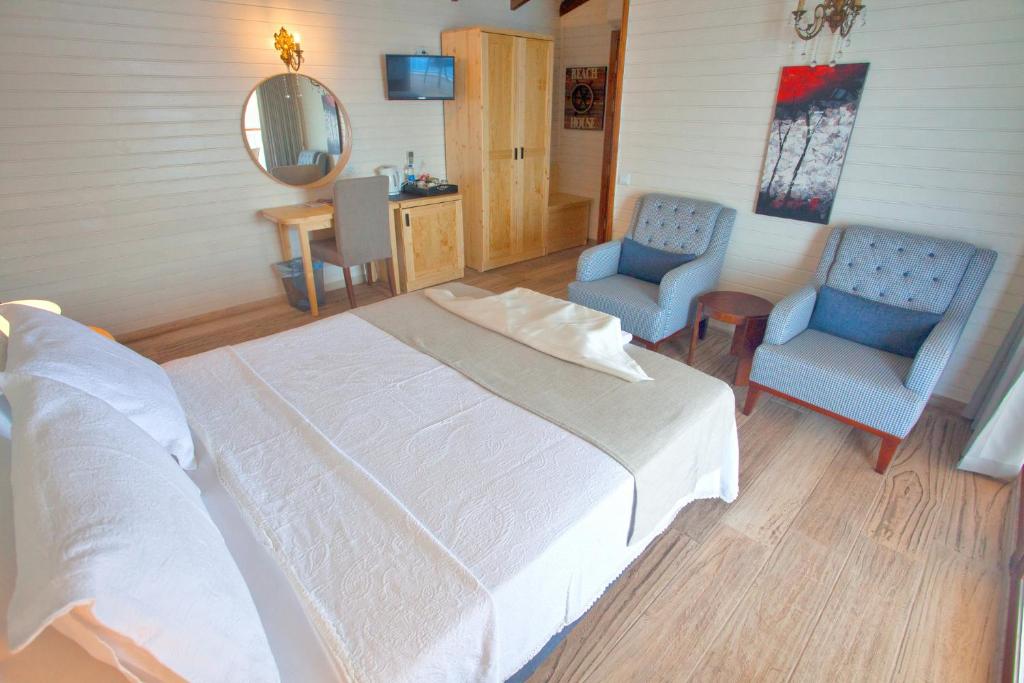 a bedroom with a white bed and two blue chairs at Sunset Villa Hotel in Kaş