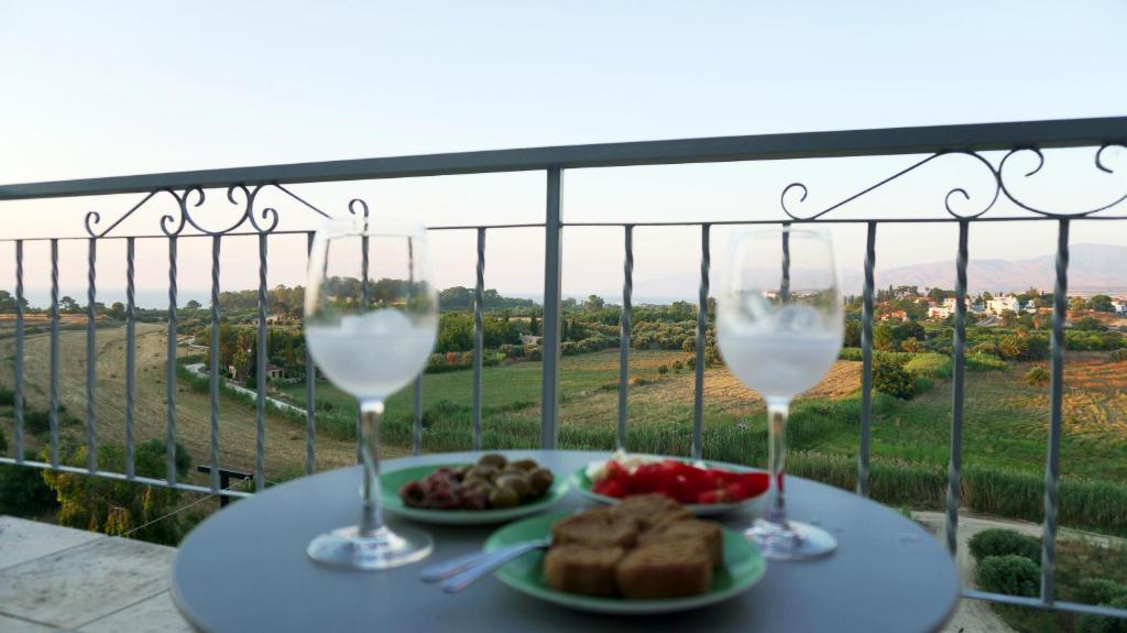zwei Gläser Wein und ein Teller Essen auf dem Tisch in der Unterkunft Panoramic sea view apartment in Polis-Latchi in Polis Chrysochous