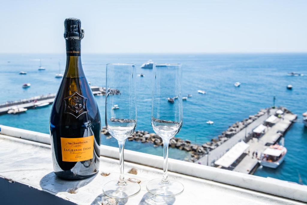 a bottle of wine and two wine glasses on a ledge at Suite Picasso in Amalfi
