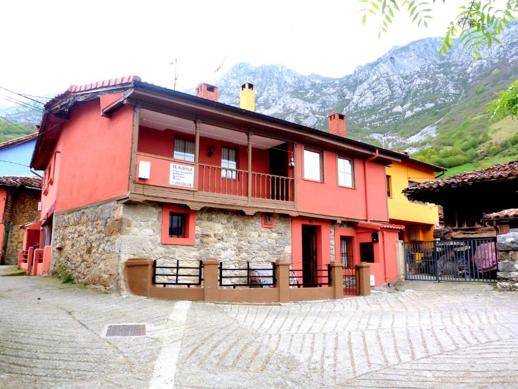 ein rotes Gebäude mit Balkon auf einer Straße in der Unterkunft Casa rural El Tejo in Bermiego