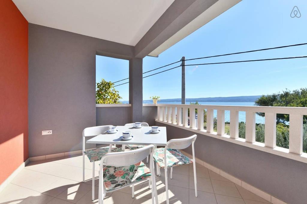 a table and chairs on a balcony with a view of the ocean at Apartments Marta in Duće