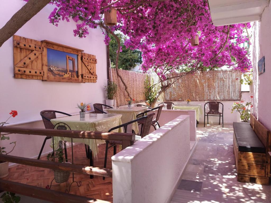 um pátio com mesas, cadeiras e flores roxas em Syrianos Hotel em Naxos Chora