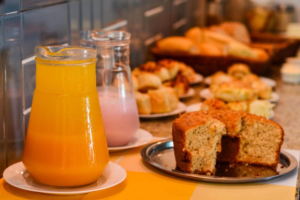 una mesa con un plato de pan y un vaso de zumo de naranja en Pousada Fernandes, en Arraial do Cabo