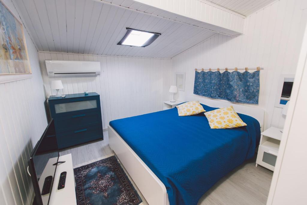 a small bedroom with a blue bed and a tv at Hotel Como in Siracusa