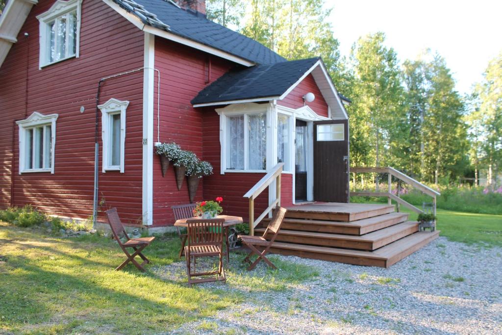 een rood huis met een veranda en een tafel en stoelen bij Villa Havula in Ranua