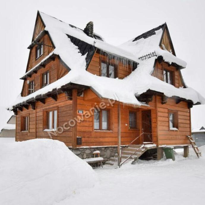 Cabaña de madera con nieve en el techo en Góralski domek en Ząb