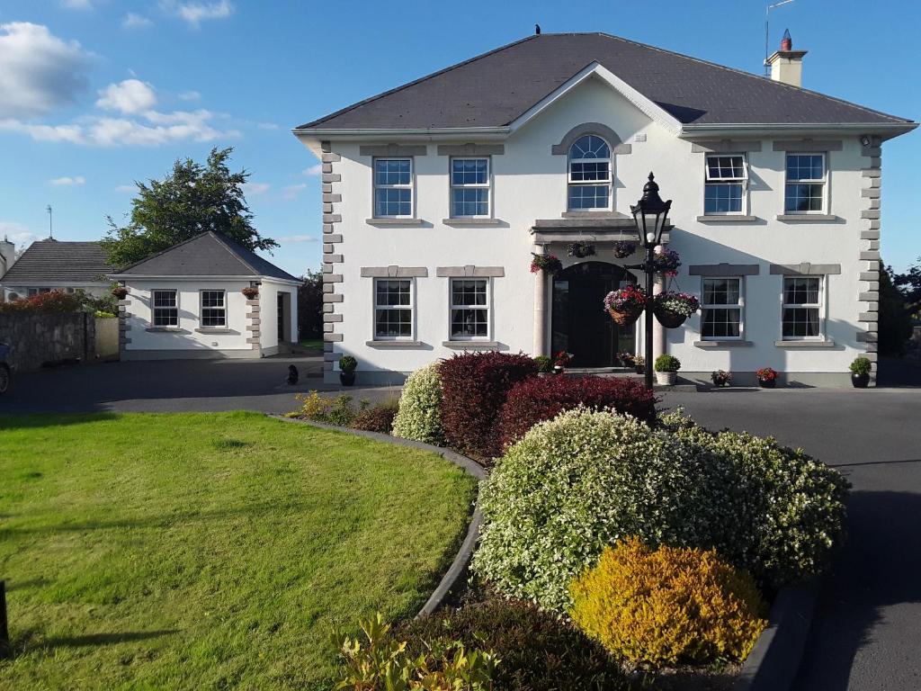 a white house with a porch and a driveway at Doonard Manor B&B in Craughwell