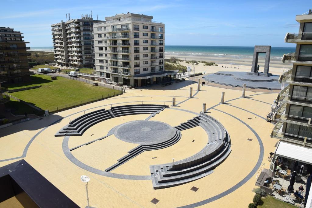 um grande relógio na praia perto de um edifício em plaza em De Panne