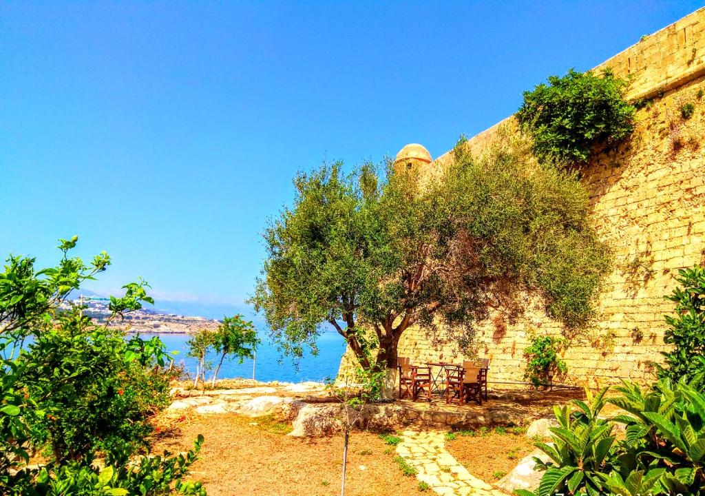 un albero accanto a un muro di mattoni con tavolo e panca di Casa di Maria a Rethymno