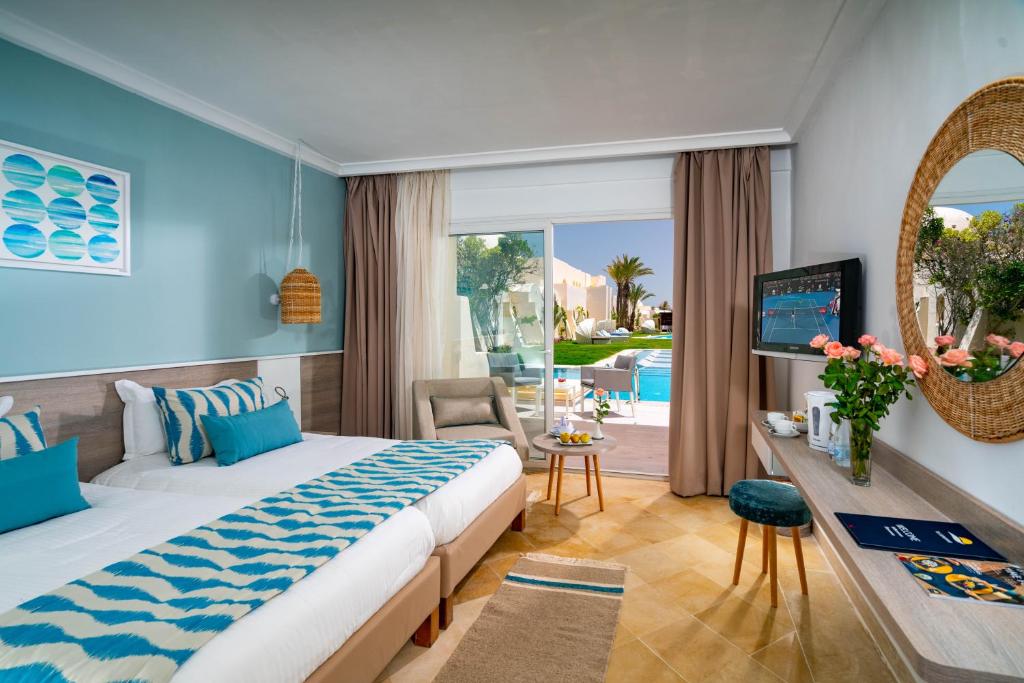 een slaapkamer met een bed en uitzicht op een zwembad bij Ulysse Djerba Thalasso & SPA in Houmt Souk