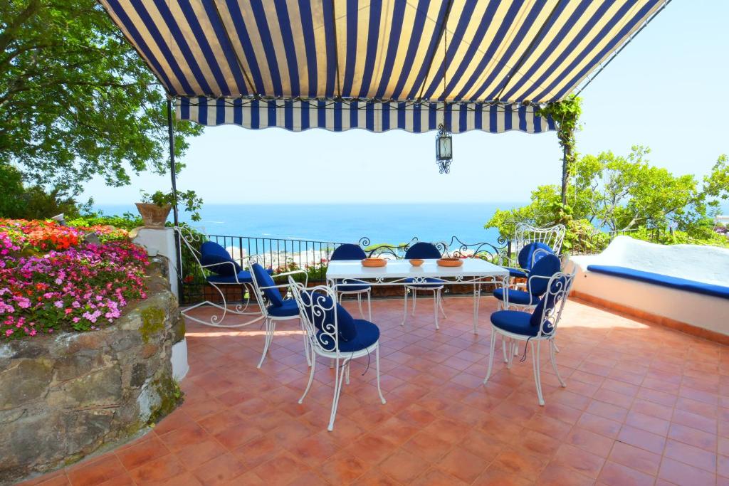 une terrasse avec une table et des chaises et l'océan dans l'établissement Aglaia Luxury Seaview Villa, à Ischia