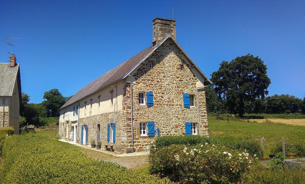 Cette ancienne maison en pierre est dotée de fenêtres bleues et d'une pelouse. dans l'établissement Le Douitel, à Roncey