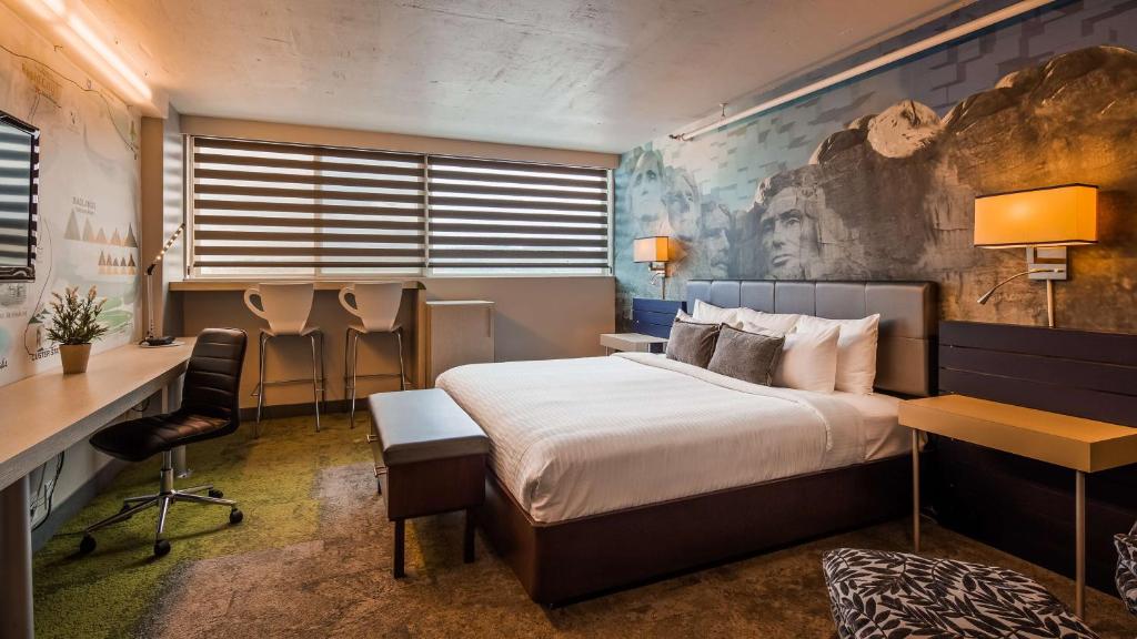 a hotel room with a bed and a desk at The Rushmore Hotel & Suites; BW Premier Collection in Rapid City