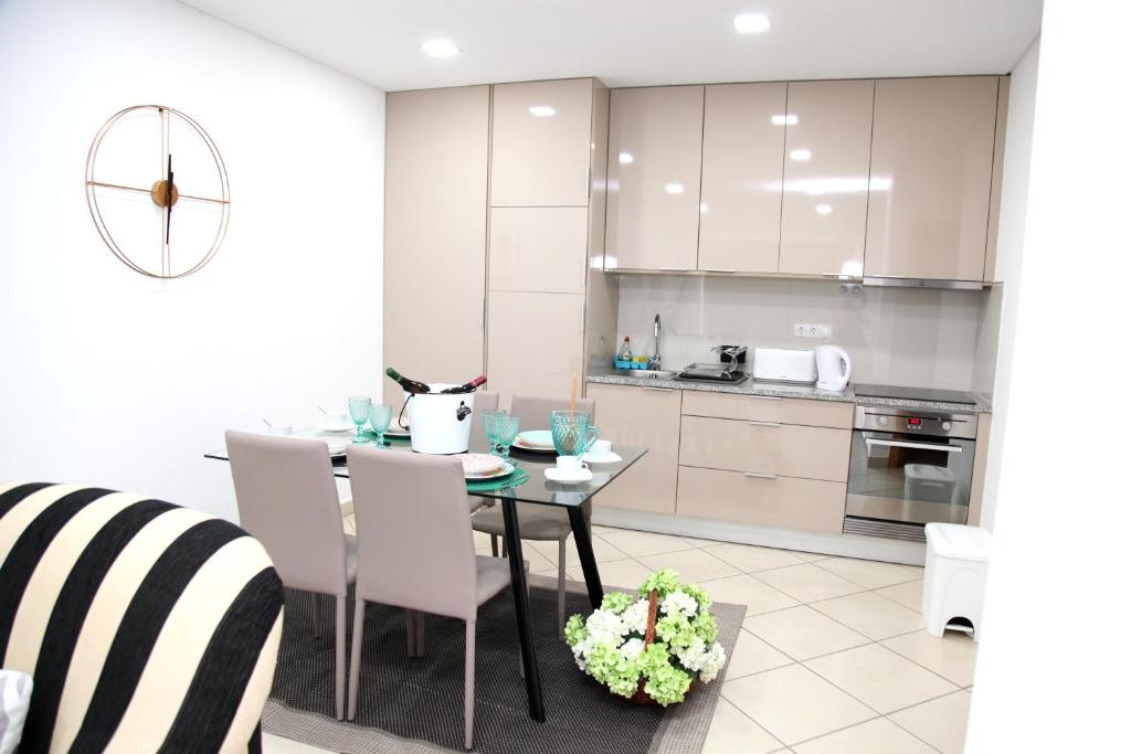 a kitchen with a dining room table with white cabinets at Casa do adro 3 in São Bartolomeu de Messines