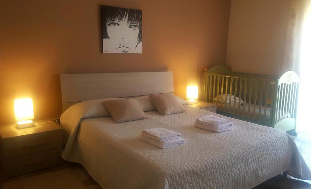 sypialnia z białym łóżkiem i 2 ręcznikami w obiekcie Appartamento Etna w mieście Giarre