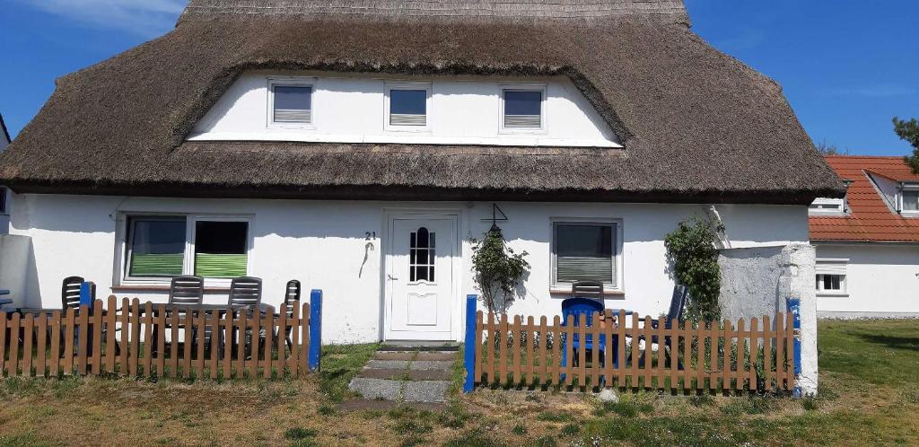 a white house with a thatched roof with a fence at Ferienwohnungen Plogshagen_Hiddens in Neuendorf